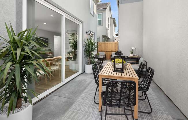 Spacious Patio with Table and Chairs, Area Rug, Potted Plants, Patio Chairs, and Sliding Glass Door to Interior of Apartment at Solstice at Fiddyment Ranch, Roseville, CA, 95747