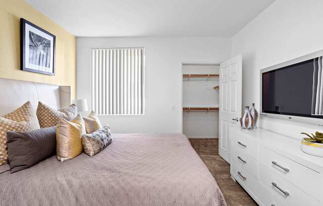 A bedroom with a bed, a dresser, and a television.