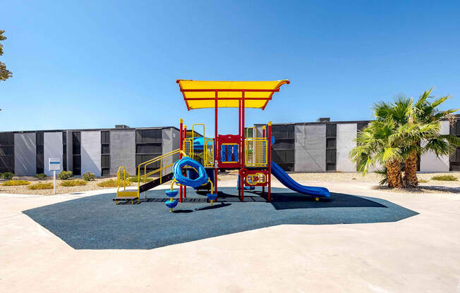 a colorful playground in front of a building with palm trees