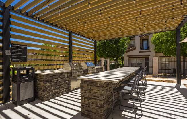 a patio with tables and chairs under a wooden roof