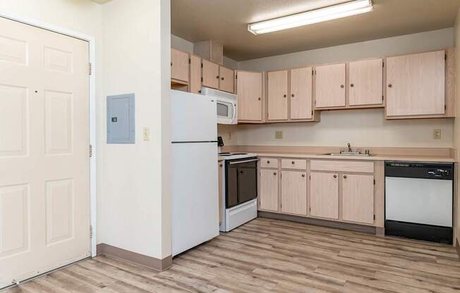 A kitchen with wooden floors and a white refrigerator.