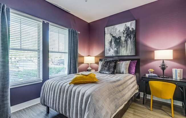 a bedroom with purple walls and a bed with a striped comforter