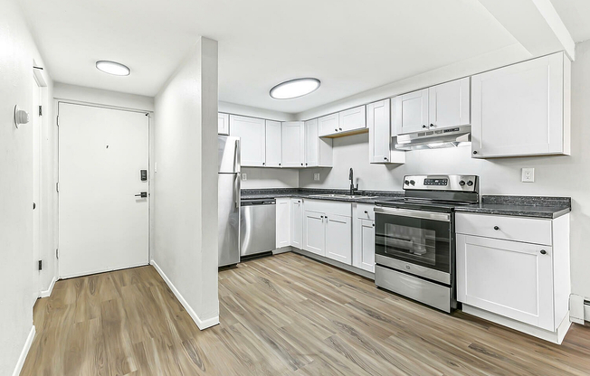 Bright and modern kitchen with sleek white cabinets, stainless steel appliances, and elegant wood flooring.