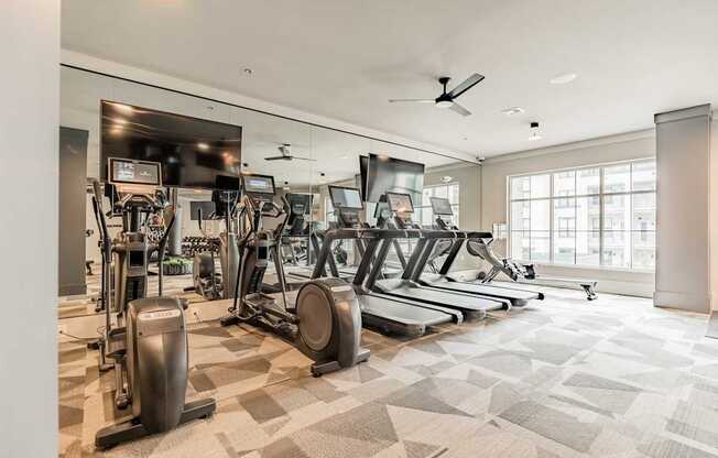 A spacious gym with a variety of equipment including treadmills, elliptical machines, and a stationary bike.