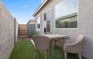 a patio with a table and chairs in front of a house