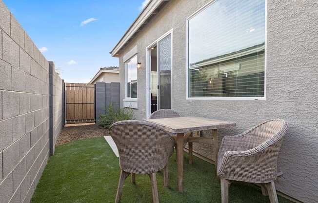 a patio with a table and chairs in front of a house