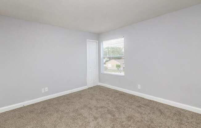 A room with a carpeted floor and a window.