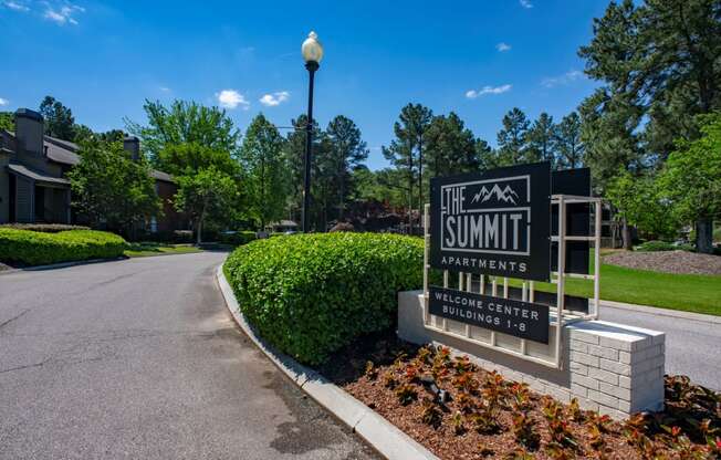 the summit apartments sign in front of a road with trees at The Summit Apartments, Memphis