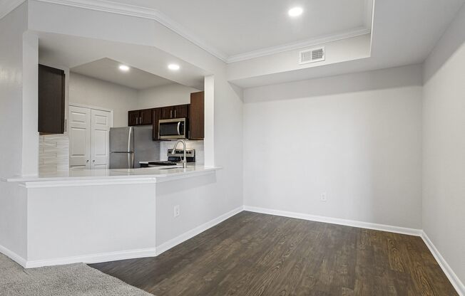an empty living room with a kitchen and a hard wood floor at The Legends at Eagle Mountain Lake, Fort Worth, TX