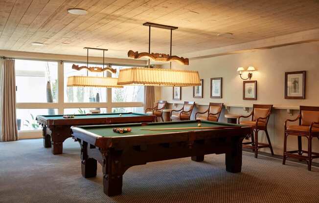 a game room with two pool tables and chairs