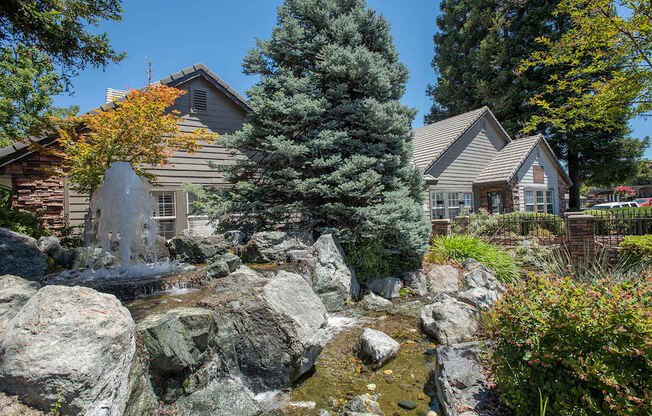 A clubhouse with a waterfall in front of it at Sunset Summit, Rocklin, CA, 95765