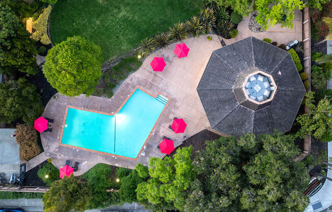 An aerial view of a pool surrounded by trees and umbrellas.