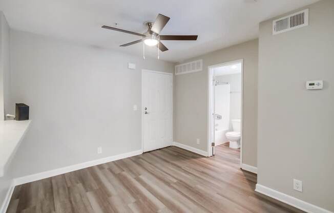 A room with a ceiling fan and wooden flooring.