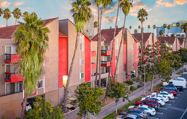 a row of townhomes with palm trees and parked cars