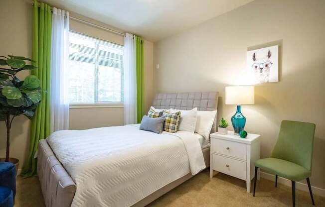 A bedroom with a white bed and a green chair.