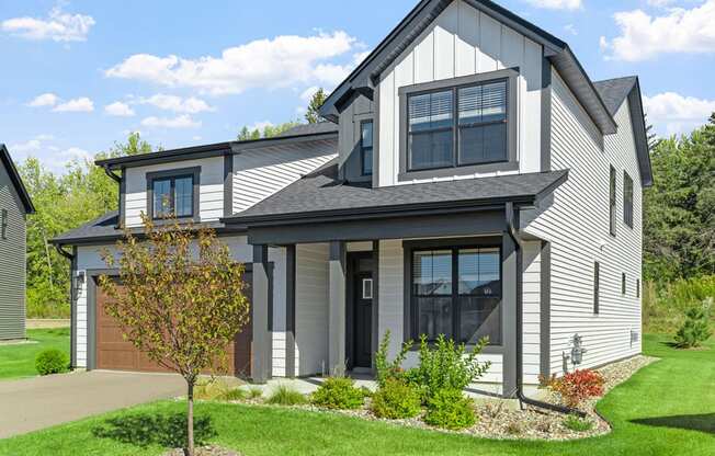 a gray house with a garage and a lawn