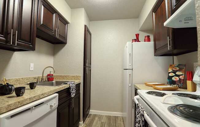 A view of the kitchen, with dark wood cupboard and new appliances at Willow Creek Apartments, Houston, TX