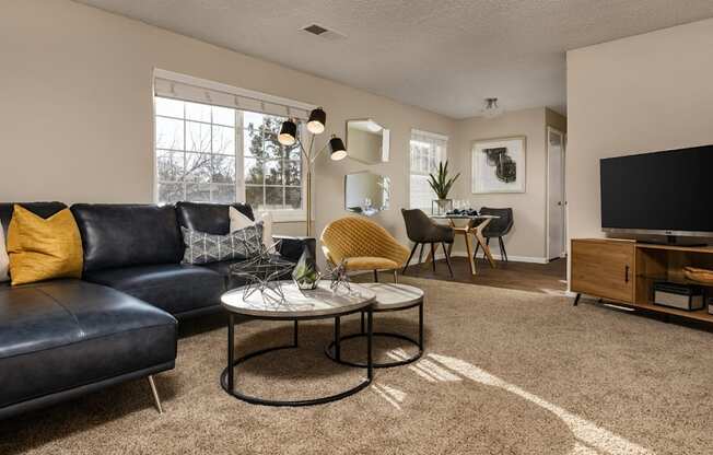A living room with a black leather couch and a coffee table.