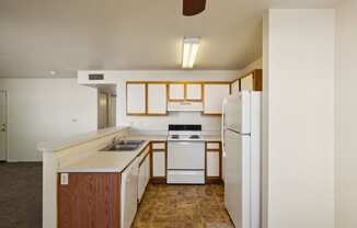 an empty kitchen with white appliances and wooden cabinets