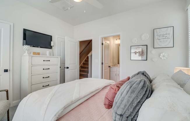 A bedroom with a bed, dresser, and a television.