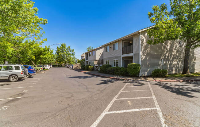 an empty parking lot in front of a building with cars parked in front