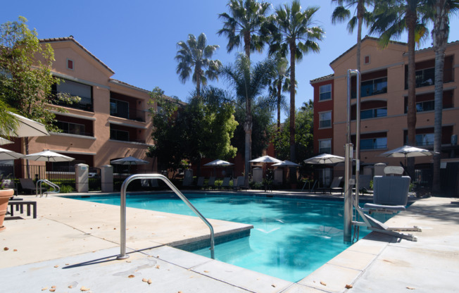 A pool surrounded by palm trees and umbrellas.