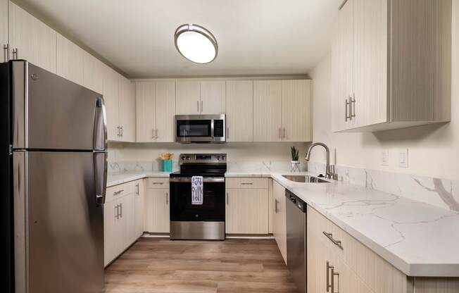 A kitchen with a refrigerator on the left and a sink on the right.