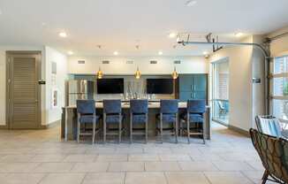 a large kitchen with a large island with blue chairs and a bar with chairs