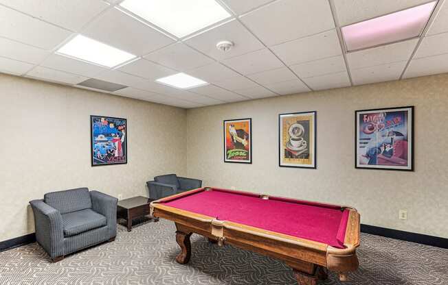 A room with a pool table and three framed pictures on the wall.