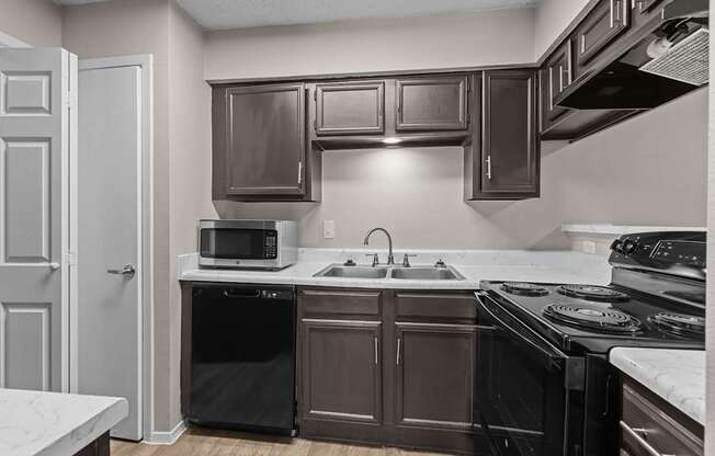 A kitchen with brown cabinets and black appliances.