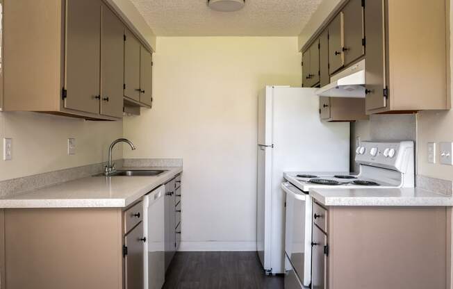 an empty kitchen with white appliances and a refrigerator