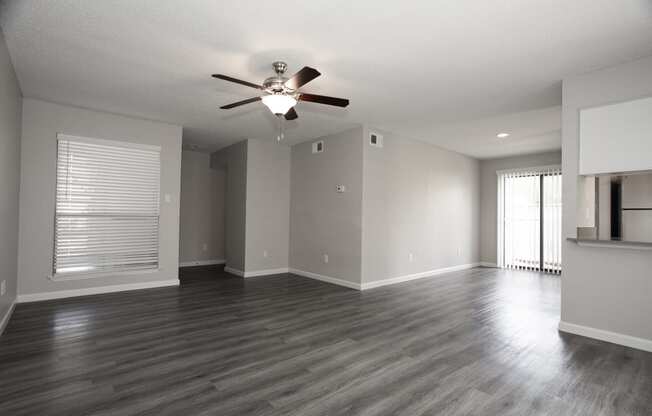 an empty living room with a ceiling fan and a window