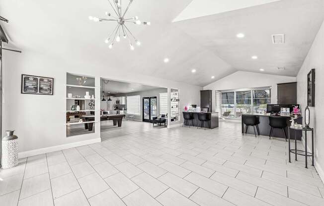 A spacious, white-walled room with a chandelier and a dining table set up.