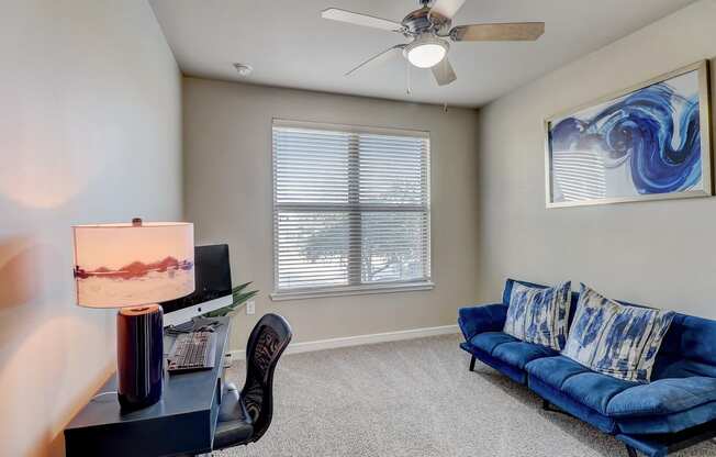 a living room with a blue couch and a ceiling fan