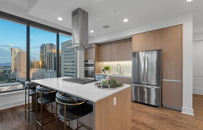 a kitchen with wooden cabinetry and a large island with a marble countertop at Stanza Little Italy, California, 92101