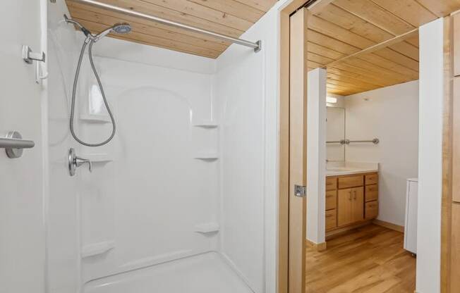 A white bathroom with wooden ceiling and floor.