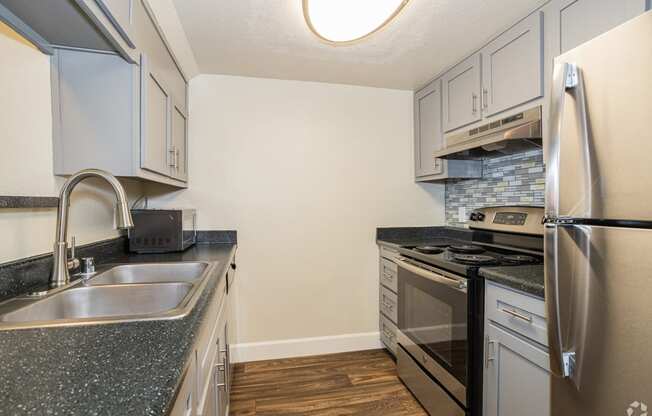 a kitchen with white cabinets and gray countertops