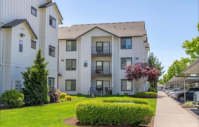 A white apartment building with a green lawn in front at Riverplace Apartment Homes, Independence, OR, 97351
