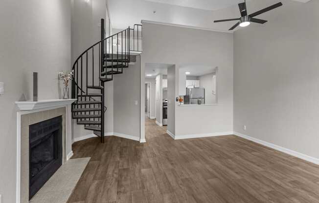 an empty living room with a fireplace and a spiral staircase