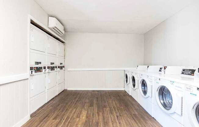 A laundry room with a row of washing machines.
