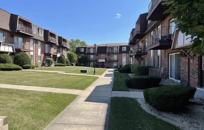 a view of an apartment complex with a grass yard and sidewalk