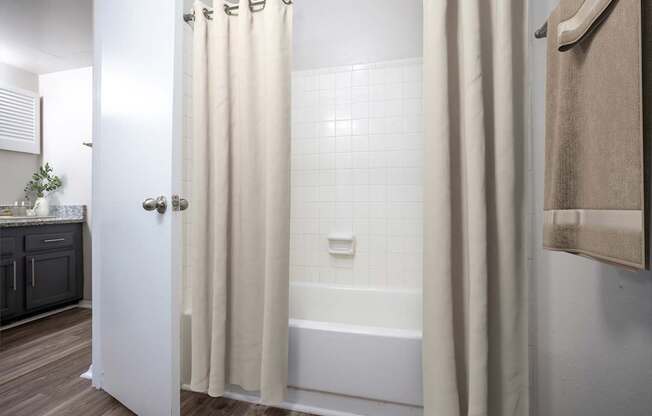 A white bathroom with a white tub and a white shower curtain.