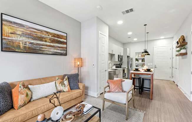 A living room with a couch, a chair, and a painting on the wall.