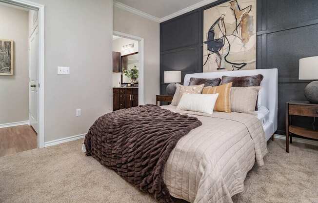 A bedroom with a large bed and a painting on the wall.