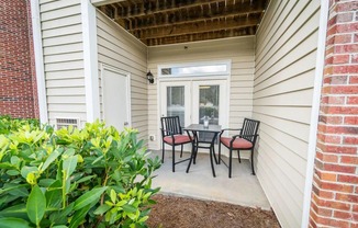 a patio with a table and chairs in front of a house