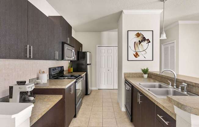 A kitchen with brown cabinets and a black microwave.