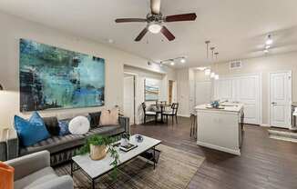 A living room with a grey couch and a painting on the wall.