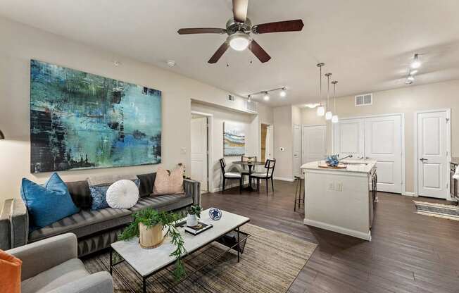 A living room with a grey couch and a painting on the wall.