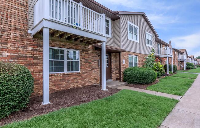 a house with a lawn in front of a brick building