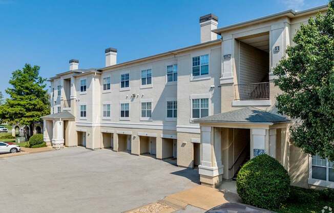 A large, multi-story apartment building with a parking lot in front.
